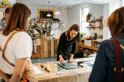 Host shows print workshop participants how to roll out paint ready to print and use to make Christmas card and gift wrap