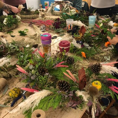Table covered in branches, leaves, flowers and pine cones used to create beautiful autumn wreath