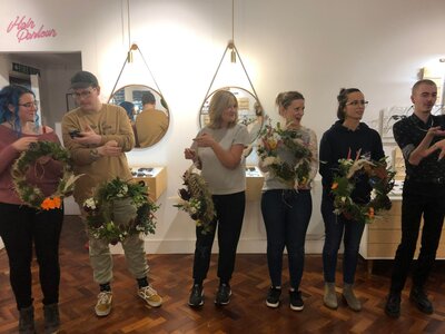 Group of guests pose together with their finished autumn wreaths