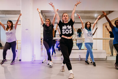 People dancing and lifting their arms up in a dance studio 