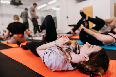 Yoga class attendant cuddles adorable puppy while other class attendants stretch