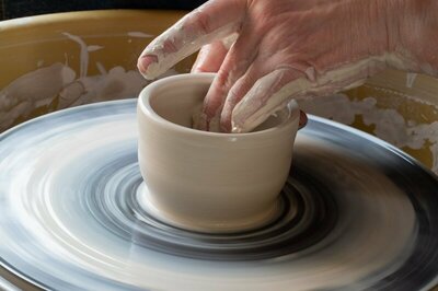 Close op on person wheel throwing piece of clay and shaping it into pot