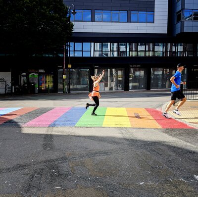 Runners run across rainbow road crossing