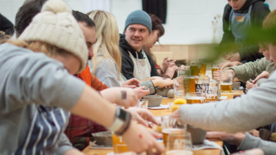 Guests sit around long table and work with clay
