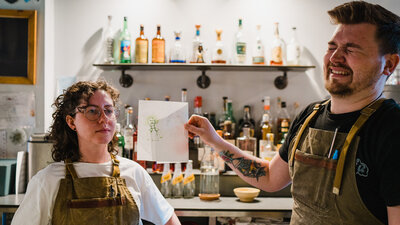Guest poses next to drawing their colleague who's laughing did of them