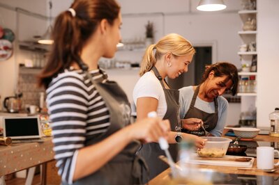 Guests laugh as they take part in cookery class 