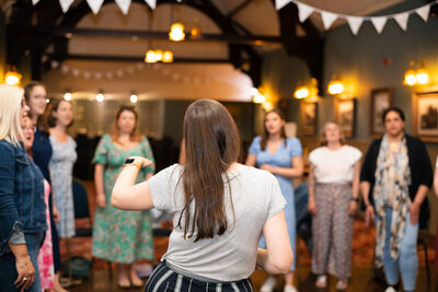 Guests and host stand in circle and practise singing techniques