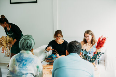 Guests sit around the table and work on their dried flower wreaths 