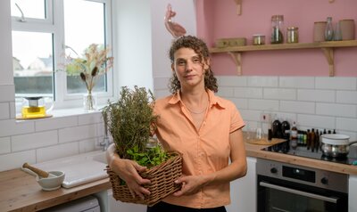 Host poses for photo holding basket filled with herbs