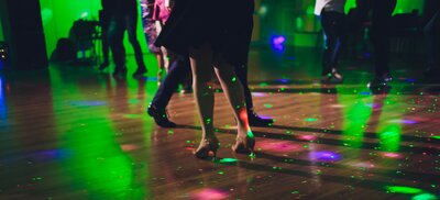 Guests dance on dance floor lit with colourful lights