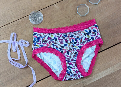 Charming handmade knickers with vibrant leaves and pink lace trim on a crafting table.