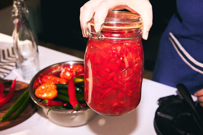 Bright jar of homemade pickled chillies in a cosy kitchen setting