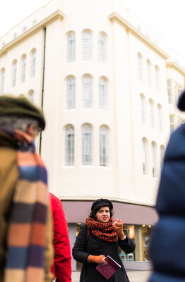 A lively city tour guide sharing stories by an elegant white building.