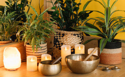 Cosy candlelit corner with lush plants and singing bowls