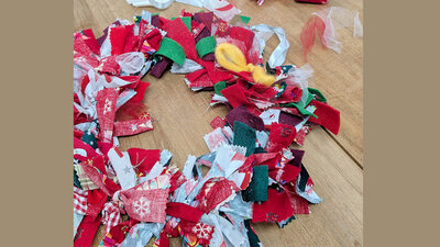 Festive fabric wreath with colourful ribbons on a wooden table