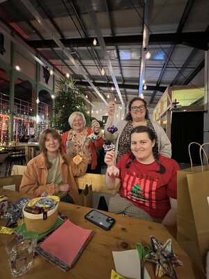 Joyful crafting group showing off handmade treasures in a cosy venue