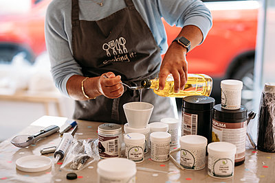 Host pours olive oil onto a spoon during a workshop
